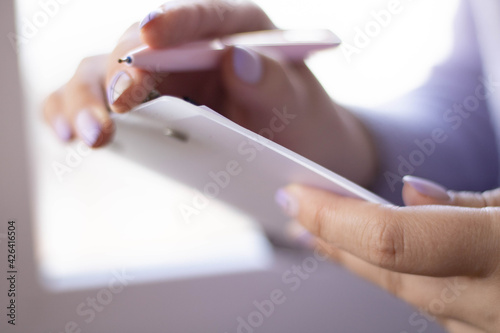 Woman hand holding wooden clipboard and a pen on background