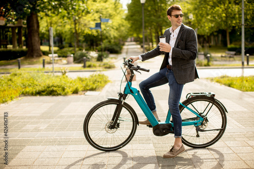 Young businessman on the ebike with takeaway coffee cup