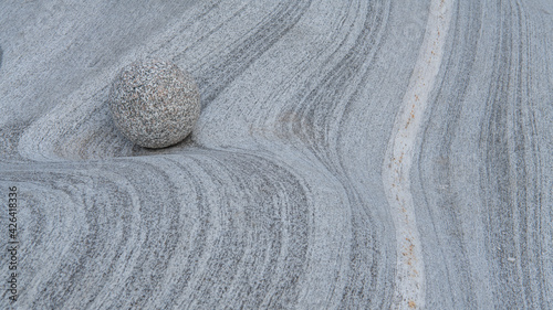 Canvas Print Close up of one round stone on grey granite  stone waves made by crystal clear water
