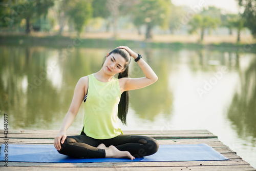 Young women stretch their muscles on a yoga mat outdoors in the park © atsarapong