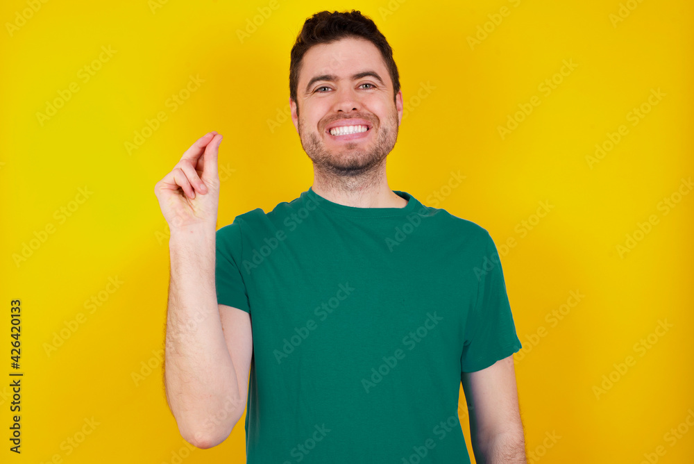 young handsome caucasian man wearing green t-shirt against yellow background pointing up with hand showing up seven fingers gesture in Chinese sign language QÄ«. young handsome caucasian man wearing green t-shirt against yellow background pointing up with hand showing up seven fingers gesture in Chinese sign language QÄ«.