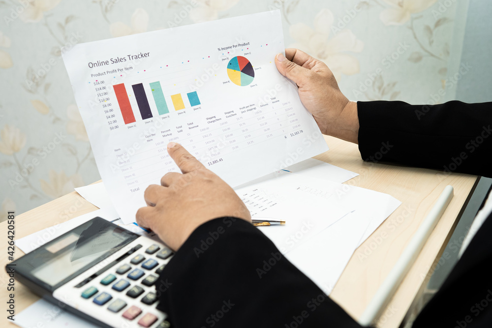 Asian accountant working and analyzing financial reports project accounting with chart graph and calculator in modern office, finance and business concept. Asian accountant working and analyzing financial reports project accounting with chart graph and calculator in modern office, finance and business concept.