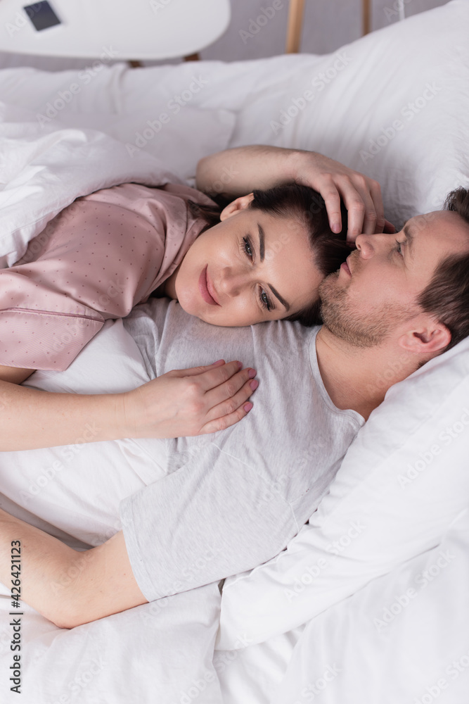Adult woman lying on chest of husband on bed Adult woman lying on chest of husband on bed