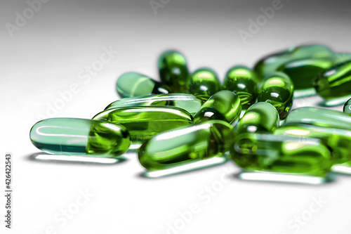 Pharmaceutical medicine colorful pills on the table, green capsules on white background