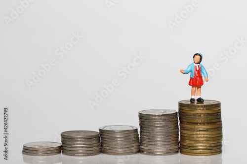 Investment planning for Kid future concept, girl doll stand on coin with white background.