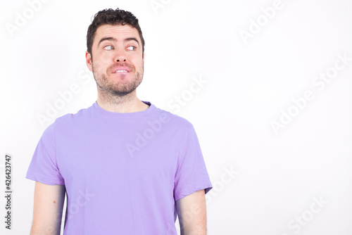 young handsome caucasian man wearing purple t-shirt against white background laughing.