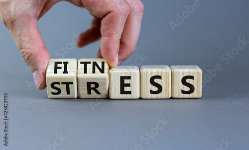 Fitness vs stress symbol. Doctor turns cubes and changes the word 'stress' to 'fitness'. Beautiful grey table, grey background. Medical, psychological, fitness vs stress concept. Copy space.