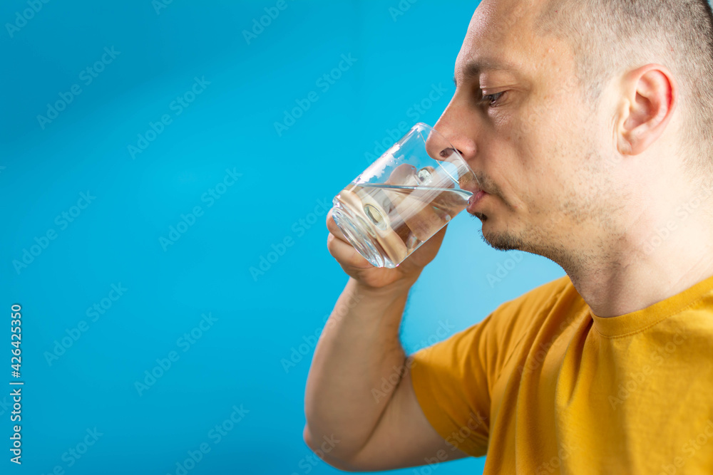 Man drinking water isolated in studio. A man drinks water from a glass. handsome man wearing glasses and shirt. Standing drinking glass of healthy water to refreshment over isolated white background Man drinking water isolated in studio. A man drinks water from a glass. handsome man wearing glasses and shirt. Standing drinking glass of healthy water to refreshment over isolated white background