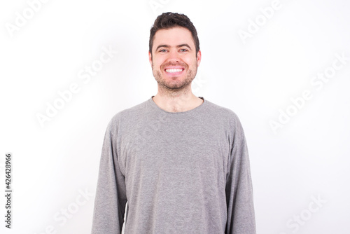 young handsome caucasian bearded man wearing pyjama over white wall with nice beaming smile pleased expression. Positive emotions concept