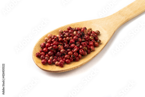 Closeup of dried red pepper grains on a wooden spoon isolated over white background