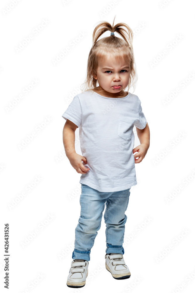 Angry little girl 2 years old in jeans and a white T-shirt. Anger, aggression and resentment. Isolated on white background. Vertical. Full height. Angry little girl 2 years old in jeans and a white T-shirt. Anger, aggression and resentment. Isolated on white background. Vertical. Full height.