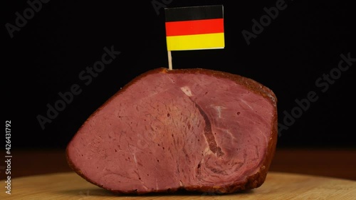 Person placing decorative Germanic flag toothpicks into piece of red meat.