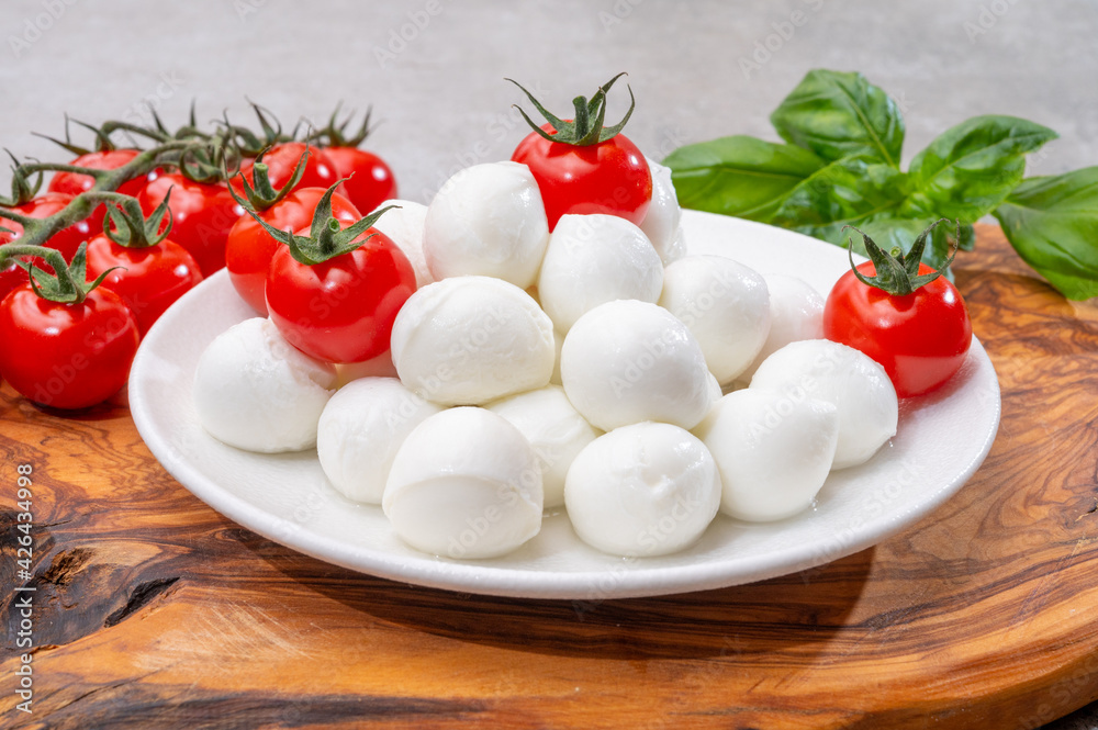 Italian tricolore, small balls of fresh white soft Italian mozzarella cheese, ripe red cherry tomatoes and fresh green basil herb, ready for making caprese salad Italian tricolore, small balls of fresh white soft Italian mozzarella cheese, ripe red cherry tomatoes and fresh green basil herb, ready for making caprese salad