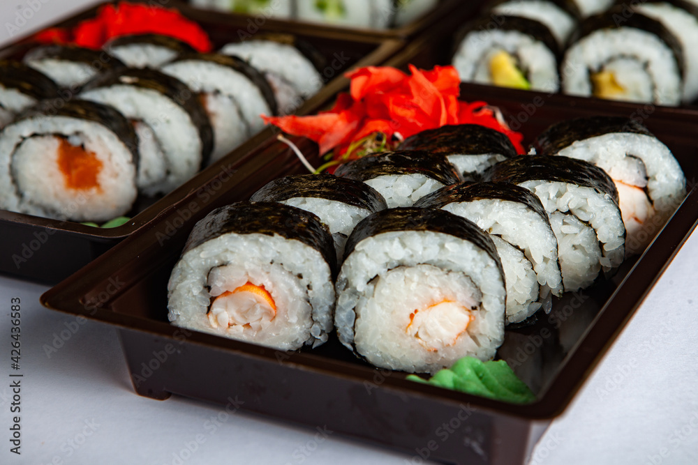 Japanese food rolls in plastic box. Sushi set in a plastic package close up isolated on a white background. Sushi for take away or sushi delivery. Japanese food rolls in plastic box. Sushi set in a plastic package close up isolated on a white background. Sushi for take away or sushi delivery.