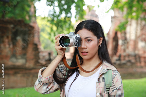 Potrait young woman toruist holding a camera , shooting a photo during outdoor travel at Ayutthaya historical part one place of World heritage photo