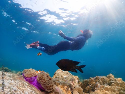 Young femal diving with snorkel and fins to see nemo fish and coral at Samaesarn Island of Thailand