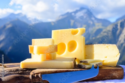 Cheese collection, French beaufort, abondance, emmental, tomme de savoie cheeses served outdoor in Savoy region, with Alpine mountains peaks on background photo