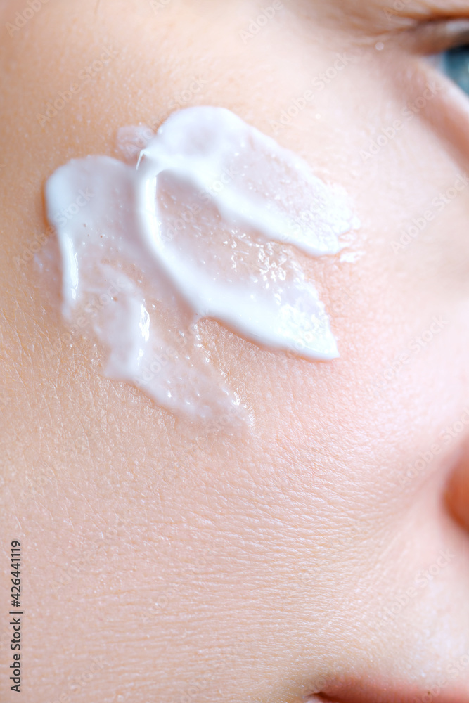 Fototapeta premium Cosmetic cream on the skin of a woman's face close-up