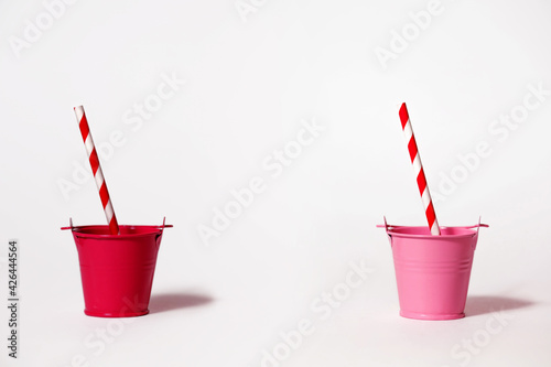 Two buckets on a white background with striped red and white straws