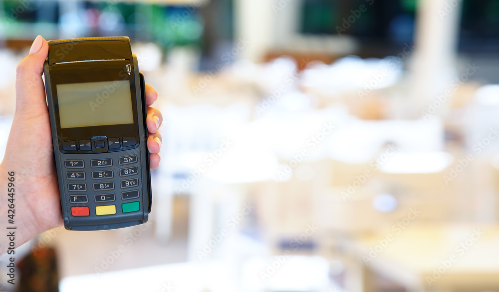 Close-up of hand using swiping machine to pay credit card. Hand with credit card reader swipe through terminal for payment. Paying by credit card.