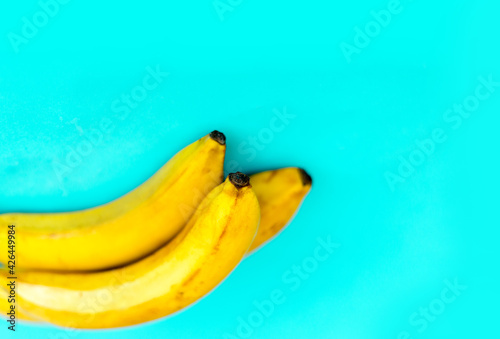 Three yellow bananas on a blue background.