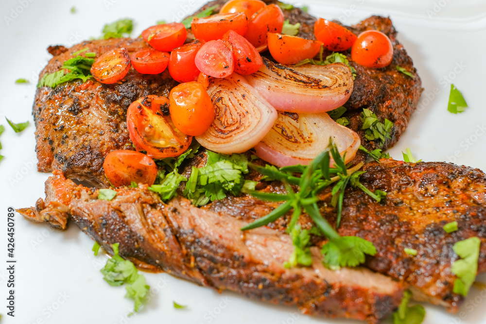 Sliced grilled beef barbecue carne asada steak with cilantro on cutting board on a gourmet dish plate