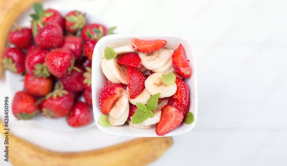 Banana strawberry salad cut into slices with mint leaves. Vitamin breakfast. Banana strawberry salad cut into slices with mint leaves. Vitamin breakfast.