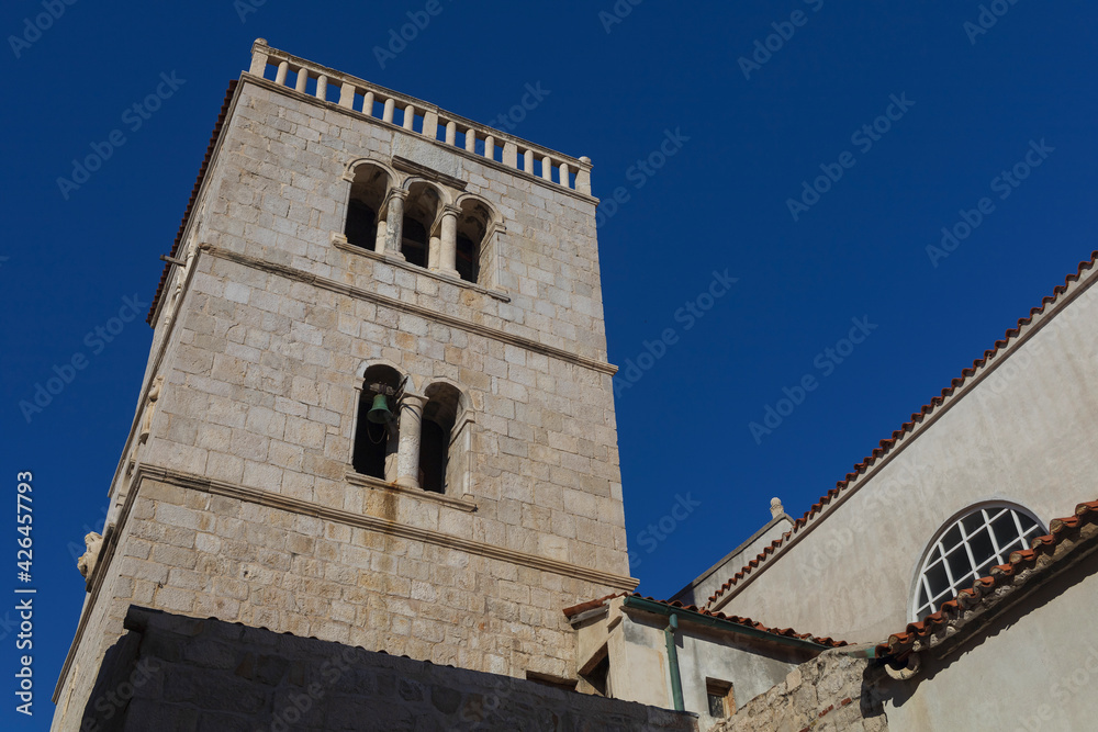 Old catholic church in historical centre of ancient Pag city with blue sky above, Croatia