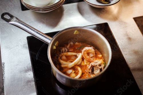 Seafood soup preparation process. Tom Yam or Bouillabaisse on induction cooker. photo