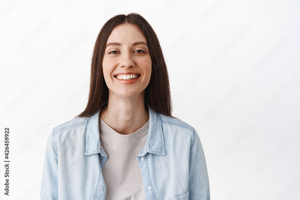 Close up of beautiful young woman with perfect white smile, nude natural skin with no make up, showing candid emotions and expressions, standing happy against white background Close up of beautiful young woman with perfect white smile, nude natural skin with no make up, showing candid emotions and expressions, standing happy against white background