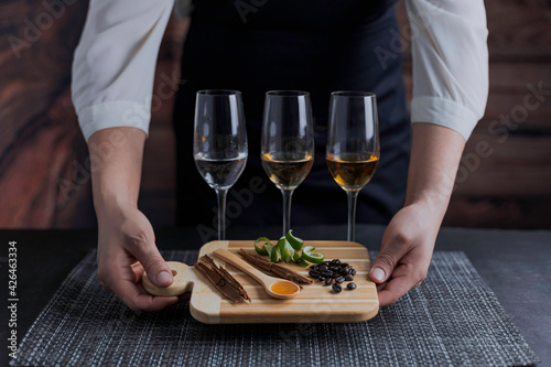 Catado de tequilas blanco, reposado y añejo. Mujer mexicana sosteniendo una tabla para cortar mostrando canela, cáscara de limón, granos de café y miel de agave.