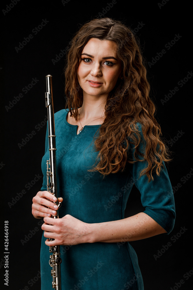 Portrait of a woman playing a transverse flute, isolated on a black background.
