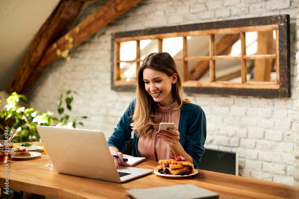 Happy businesswoman using laptop and cell phone while working at home. Happy businesswoman using laptop and cell phone while working at home.
