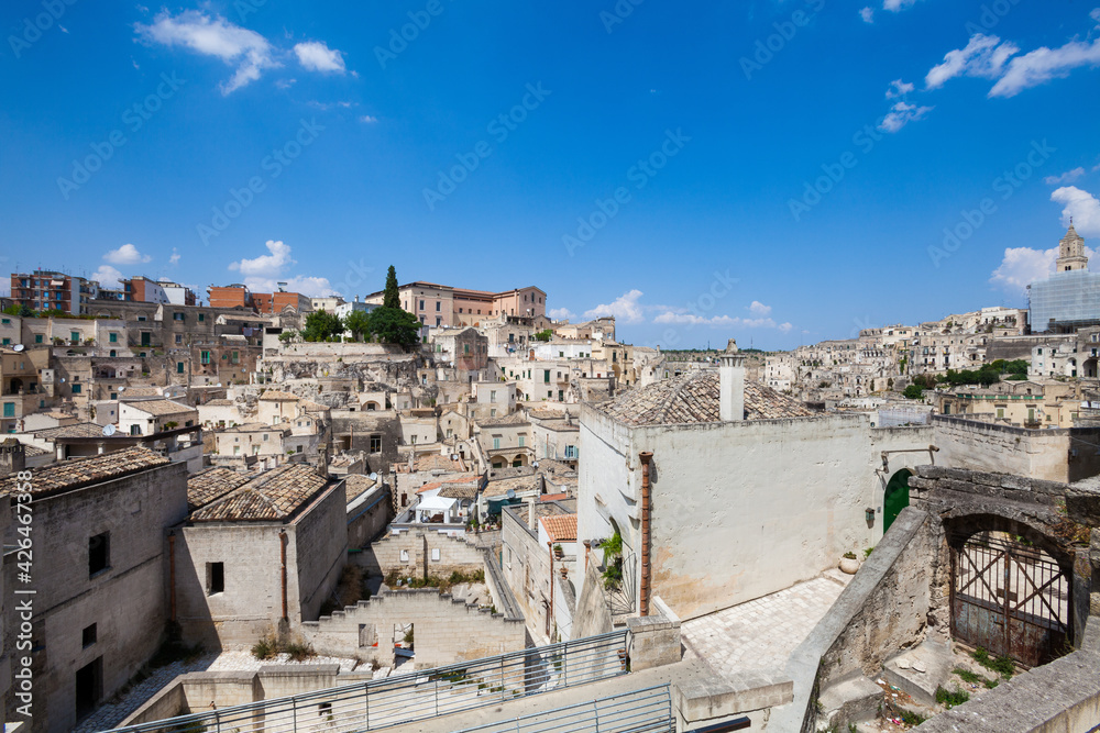 Old stones buildings and ancient Italian village in Matera in Italy. Panoramic picture of white buildings made with stones. Cluster of houses. Matera, Italy. Blue sky.