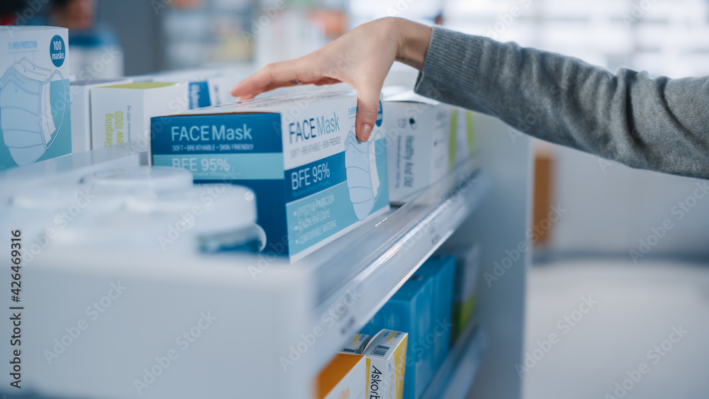 Modern Pharmacy Drugstore: Anonymous Woman Searching to Purchase Best Face Mask Package, Takes the Box. Shelves full of Health Care Products