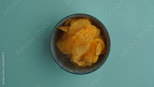 Potato chips in a deep bowl disappear and appear on a blue seamless background. Chips are a fun stop-motion game. Animated chips cookies. Homemade snacks.