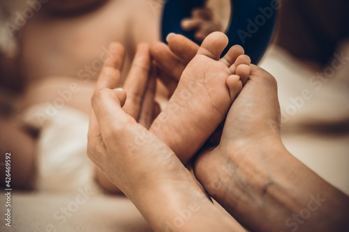 Mother's hands carefully keep baby's foot with tenderness. © Inception