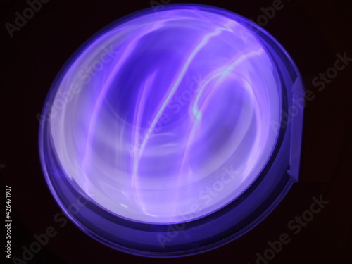 Fotografi Washing machine round blue glass door purple lighting in dark, abstract round bl