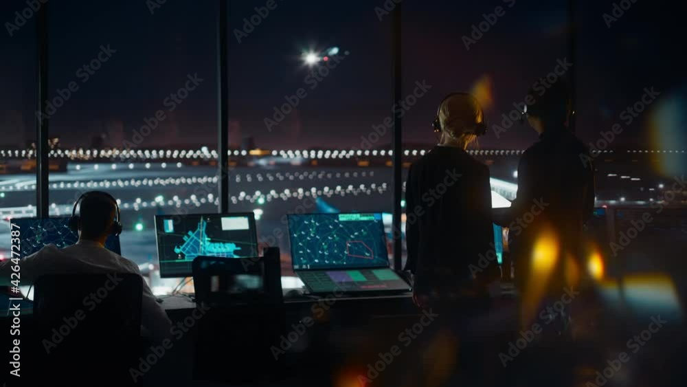 Female and Male Air Traffic Controllers with Headsets Talk in Airport Tower at Night. Office Room Full of Desktop Computer Displays with Navigation Screens, Airplane Flight Radar Data for Controllers. Female and Male Air Traffic Controllers with Headsets Talk in Airport Tower at Night. Office Room Full of Desktop Computer Displays with Navigation Screens, Airplane Flight Radar Data for Controllers.
