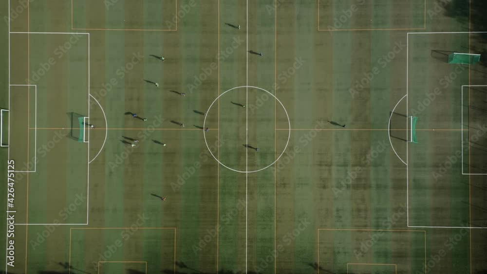 Top-down view of a soccer practice match with two professional teams playing soccer on a green field. Drone shot from top to bottom on a soccer field with two professional teams playing soccer outdoor Top-down view of a soccer practice match with two professional teams playing soccer on a green field. Drone shot from top to bottom on a soccer field with two professional teams playing soccer outdoor