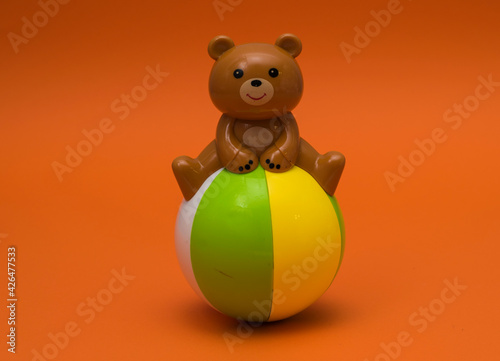 Tumbler bear on colorful ball isolated on orange background. Children's toy roly-poly close-up, fun toy for kids. photo