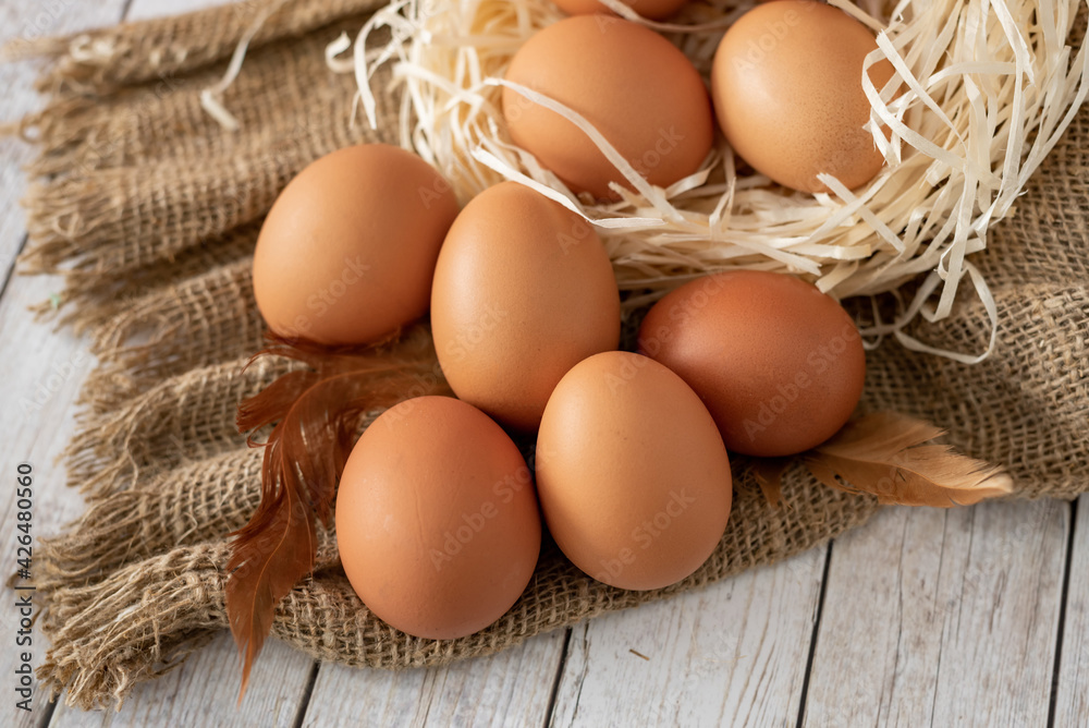 close-up of fresh farm eggs lying in the nest, on sacking with feathers. close-up of fresh farm eggs lying in the nest, on sacking with feathers.