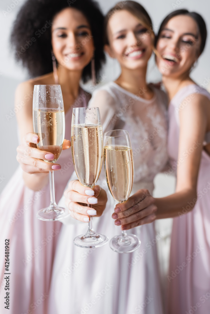 happy bride with interracial bridesmaids holding champagne glasses on blurred background. happy bride with interracial bridesmaids holding champagne glasses on blurred background.