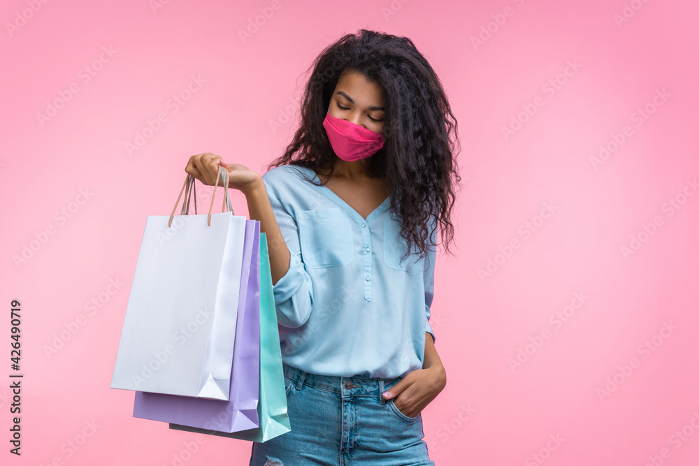Attractive african american young woman wearing pink protective face mask while making purchases