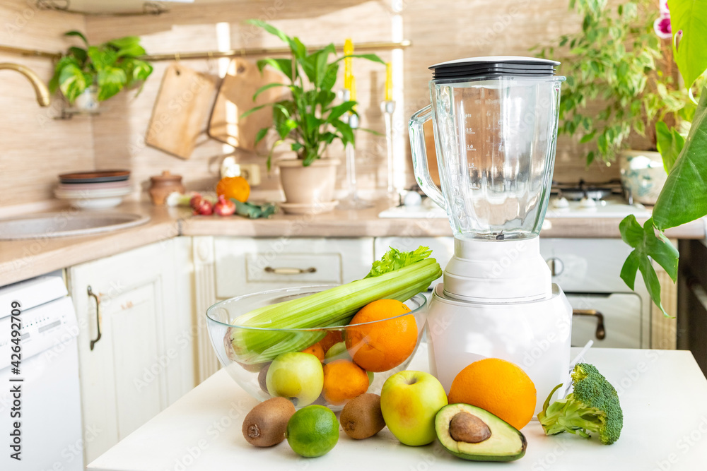 yummy ripe green fruits and vegetables on the kitchen table with a glass and blender to make a healthy and delicious green smoothie from fresh fruits and vegetables, vegan and vegetarian drink for yummy ripe green fruits and vegetables on the kitchen table with a glass and blender to make a healthy and delicious green smoothie from fresh fruits and vegetables, vegan and vegetarian drink for
