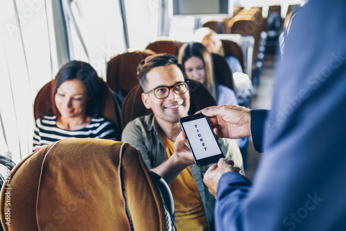 Cuadro en lienzo Young male traveler showing  e-ticket on mobile phone screen to a bus driver