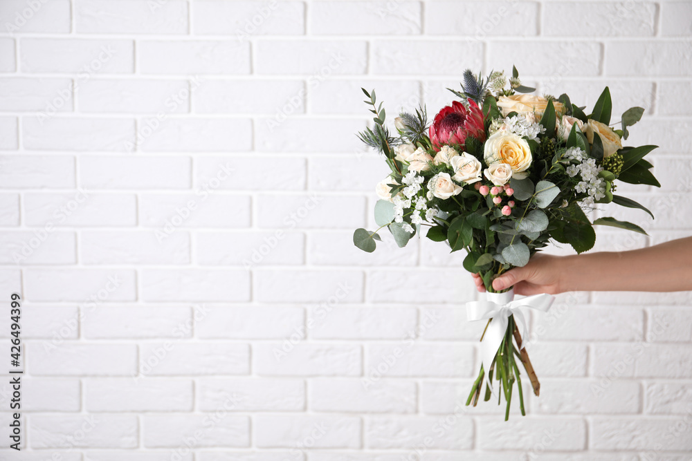 Woman with bouquet of beautiful roses near white brick wall, closeup. Space for text Woman with bouquet of beautiful roses near white brick wall, closeup. Space for text