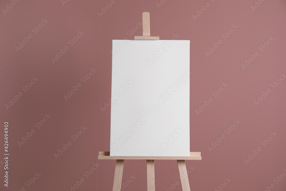 Wooden easel with blank canvas on dusty rose background Wooden easel with blank canvas on dusty rose background