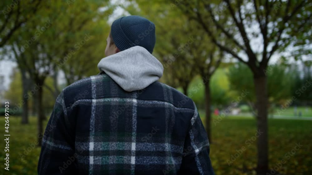 Back view of young man walking in autumn park. Close up of caucasian guy. Back view of young man walking in autumn park. Close up of caucasian guy.
