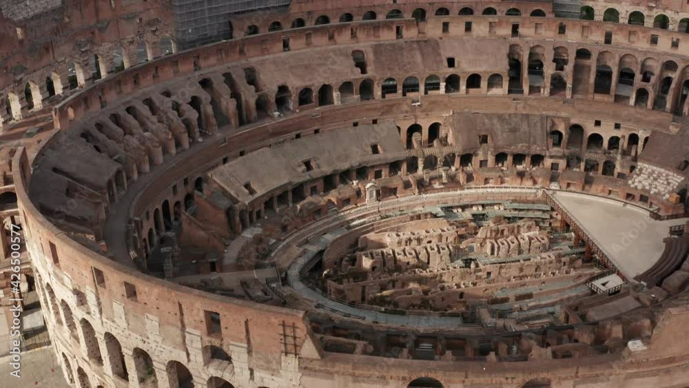 Aerial view of Colosseo or Colosseum, travel landmark in Rome, Italy. Flavian Amphitheatre or Coliseum in Roma seen from drone flying in sky. Tourist attraction with scaffolding for restoration